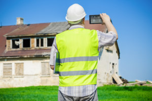 A person in safety uniform taking a picture of a house